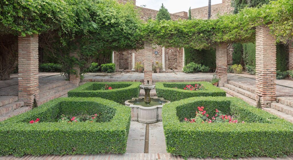 Landscaped courtyard garden with clipped hedges and a pergola inside the Alcazaba fortress in Málaga