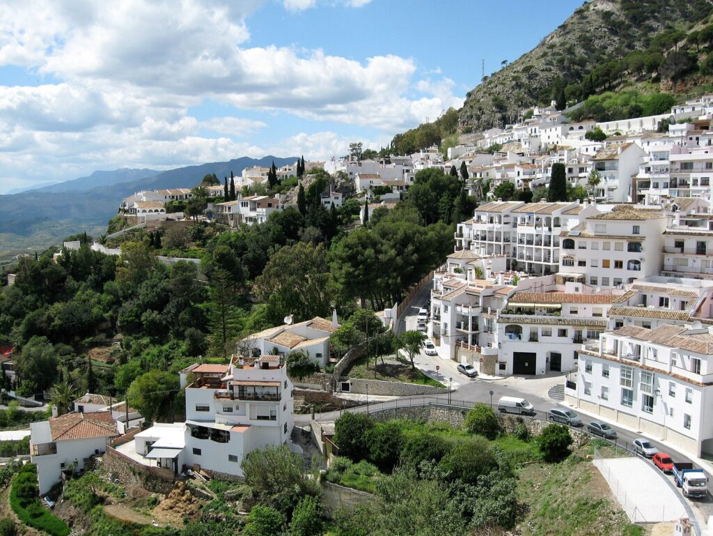 Whitewashed houses of Mijas Pueblo spread across a green hillside in the Sierra de Mijas